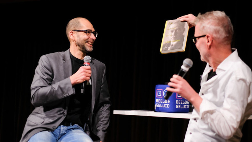 Twee mensen op een podium die een boek presenteren 