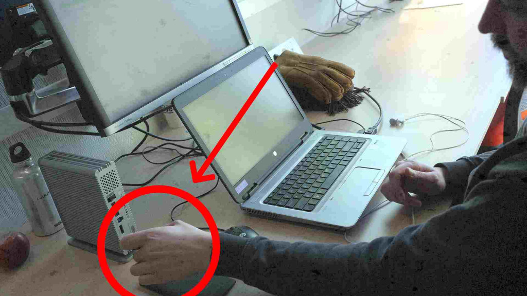 Man achter laptop met computermuis.