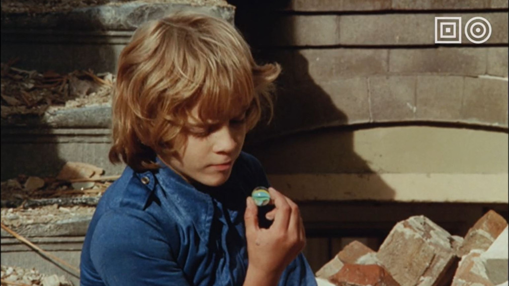 Thumbnail van de collectietrailer: Jongen kijkt in knikker, in de video zelf zitten heel veel fragmenten uit onze collectie en de breedte ervan. Van animatie, tot zeilwedstrijden en van instructievideo's tot films en series. 