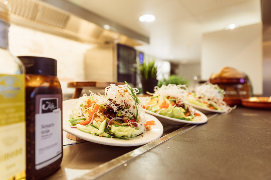 Prachtige opgemaakt borden met een kip teriyaki salade, met een kantine op de achtergrond