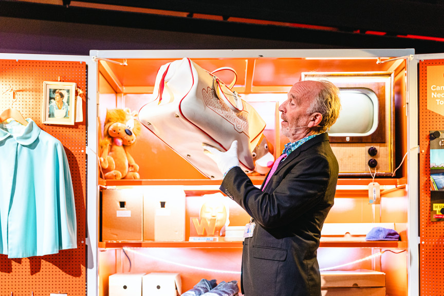Een museum docent toont de tas van sterrenslag aan de zaal. Deze tas komt uit een depotkast met allerlei voorwerpen uit de depots van Beeld & Geluid.