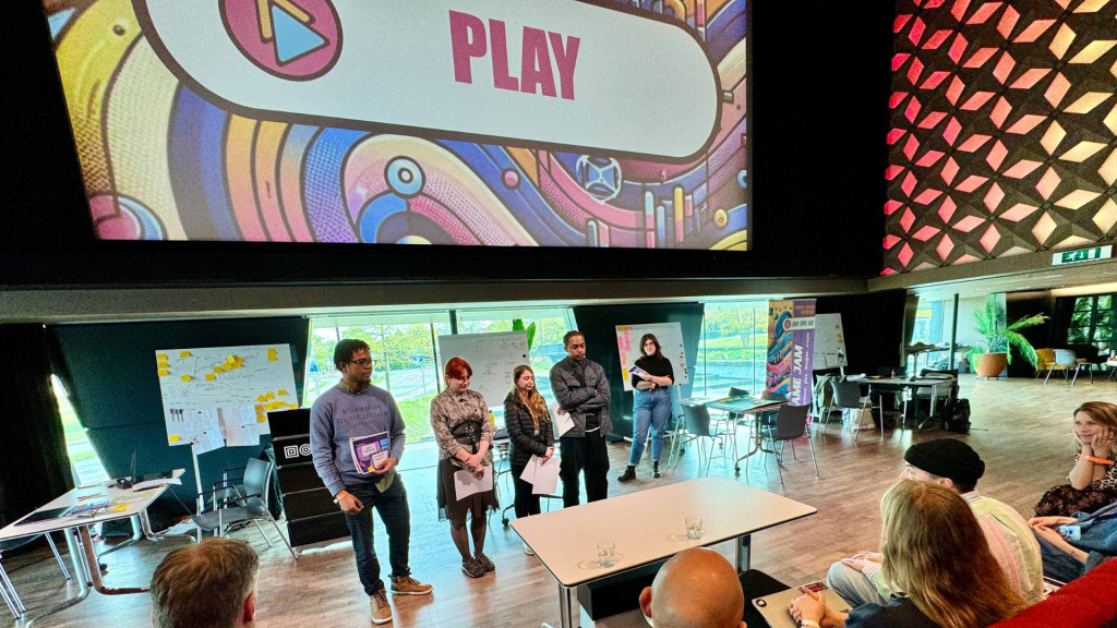 Jongeren op een rijtje voor een groot scherm in een zaal 