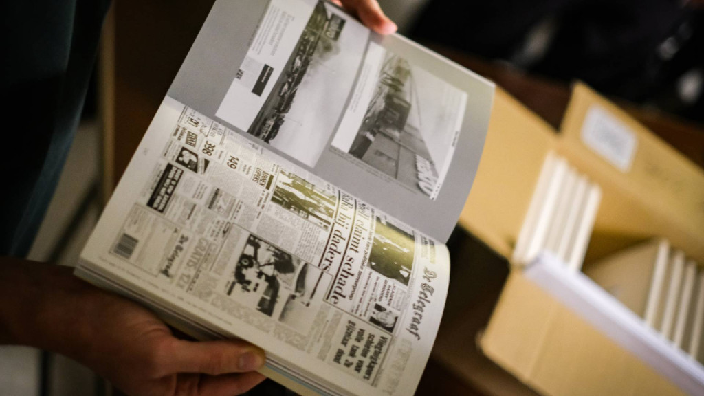 Handen die een boek vasthouden afkomstig uit een archiefdoos 