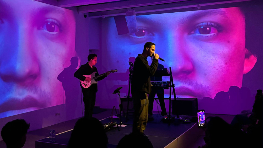 Man die zingt en op achtergrond een man met gitaar 