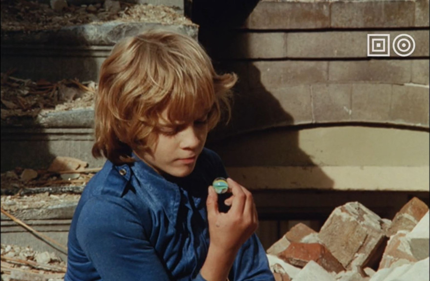 Thumbnail van de collectietrailer: Jongen kijkt in knikker, in de video zelf zitten heel veel fragmenten uit onze collectie en de breedte ervan. Van animatie, tot zeilwedstrijden en van instructievideo's tot films en series. 