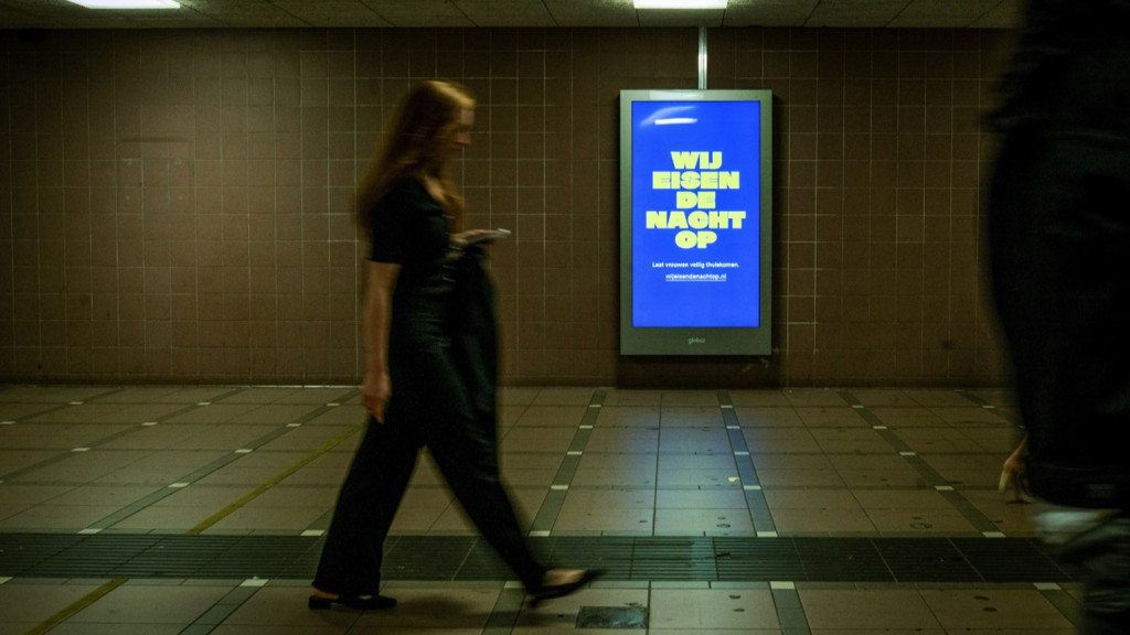 vrouw loopt alleen voorbij een bord met "wij eisen de nacht op"