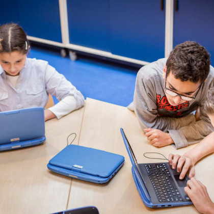 Kinderen met latops en tablet aan een tafel